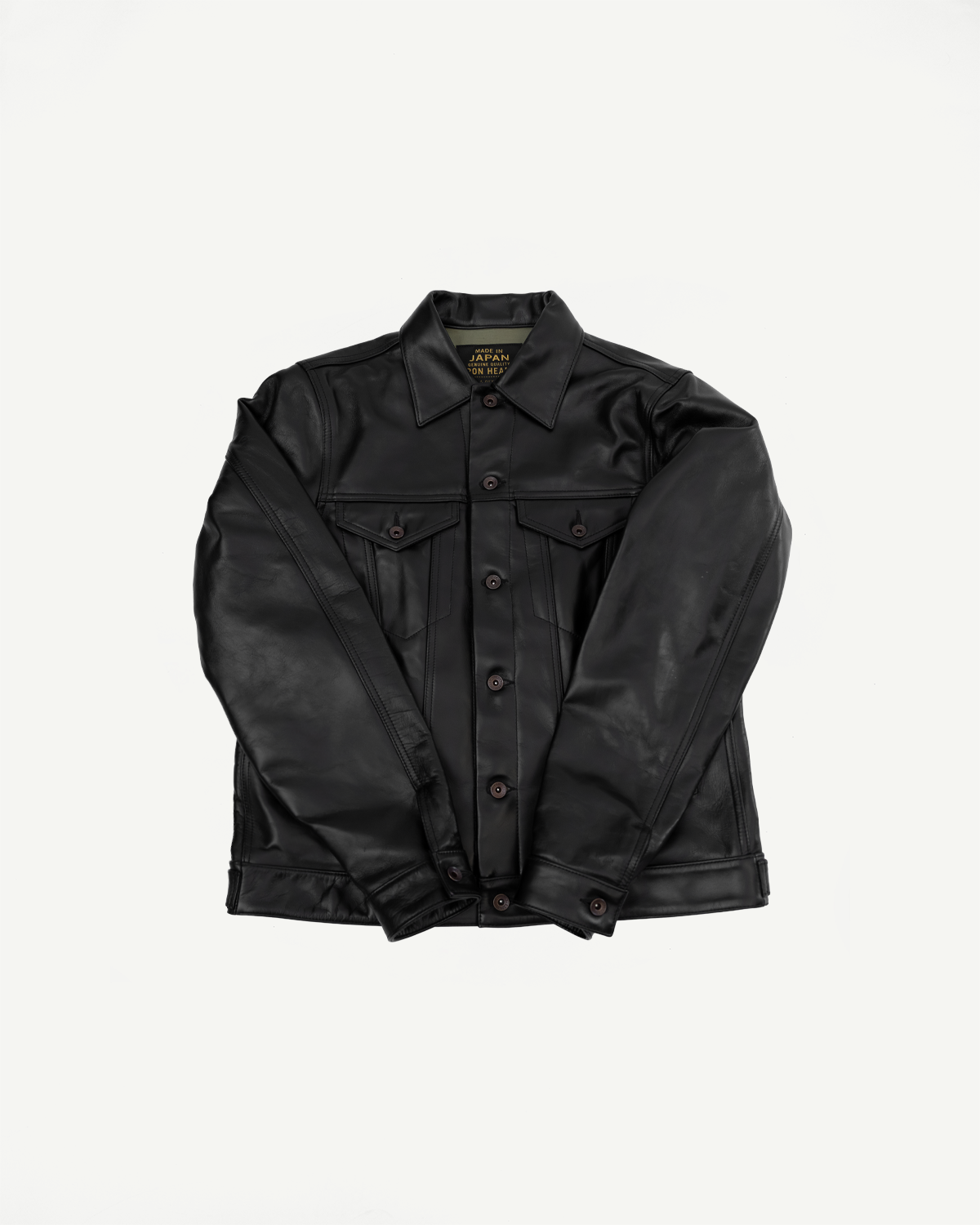 Black leather jacket flat lay, front view, snap buttons, chest pockets, collar, Made in Japan tag visible