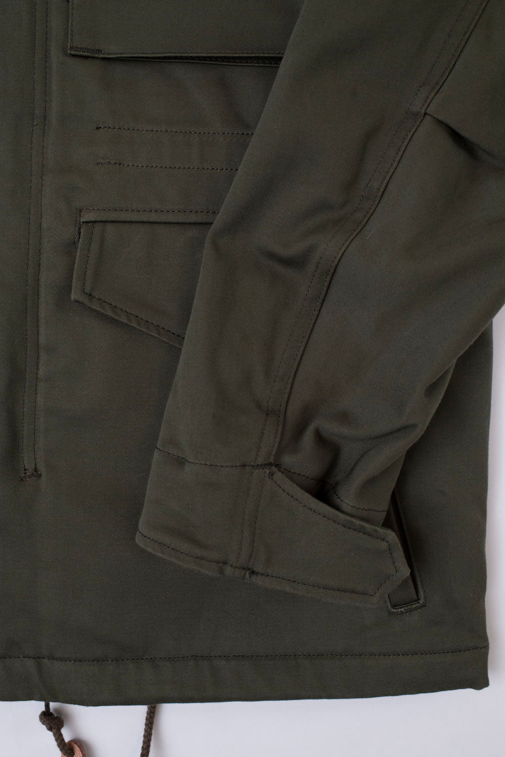 Close-up of Iron Heart IHJ-27 M65 field jacket olive, front lower right sleeve and pocket detail, showing fabric texture and stitching.