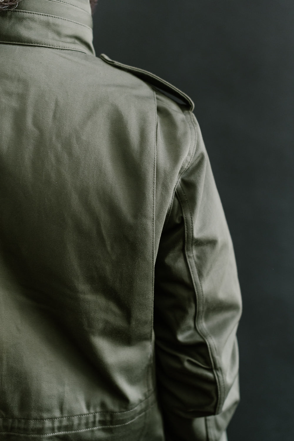 Close-up of back shoulder and collar on Iron Heart olive M65 field jacket, male model, fabric detail