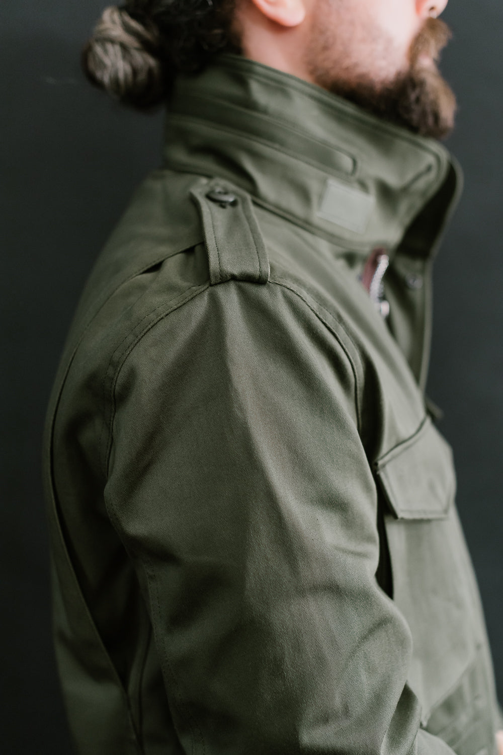Close-up right side of olive Iron Heart M65 field jacket on male model, 5'9