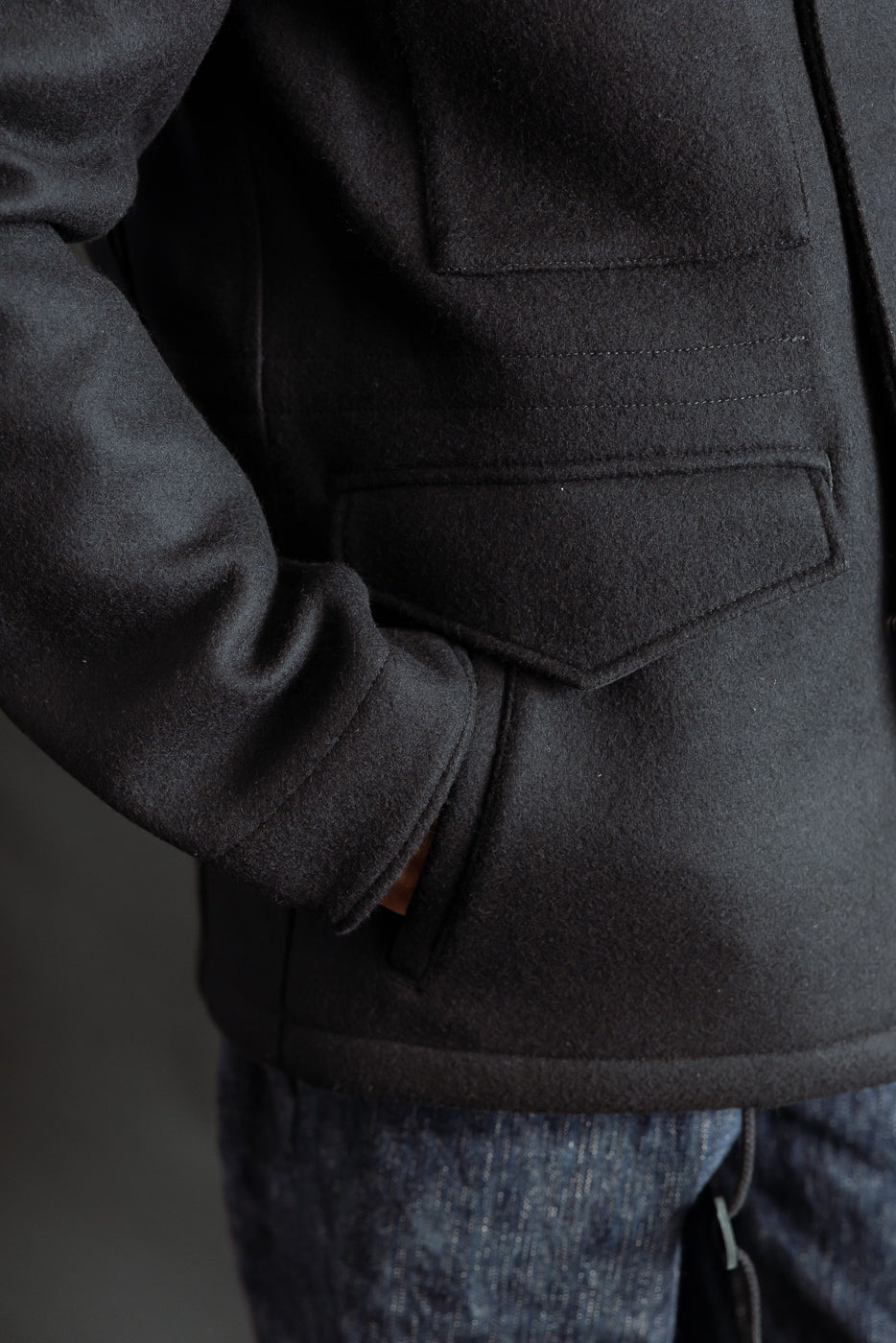 Close-up of front waist pocket and sleeve on Iron Heart black Melton wool M65 jacket, modeled by male, 5'9