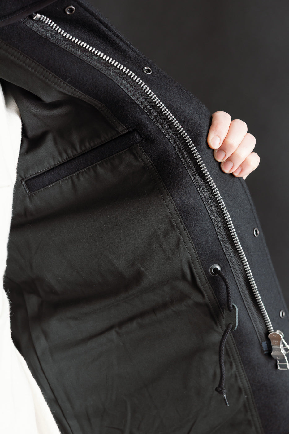 Close-up of Iron Heart M65 field jacket interior, showing inner pocket, drawstring, and zipper details.