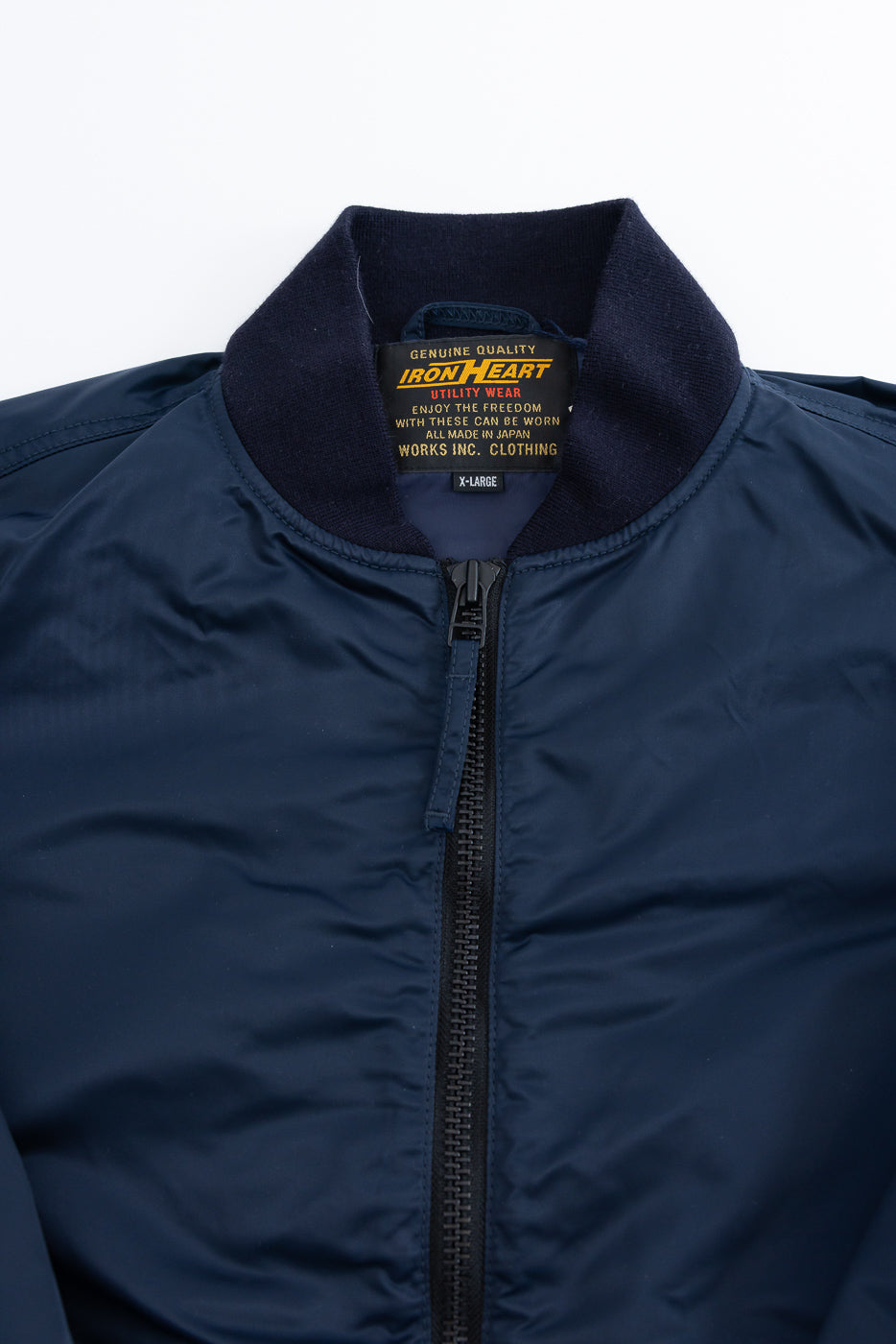 Close-up of navy nylon jacket front upper section, showing collar, zipper, and interior tag details.