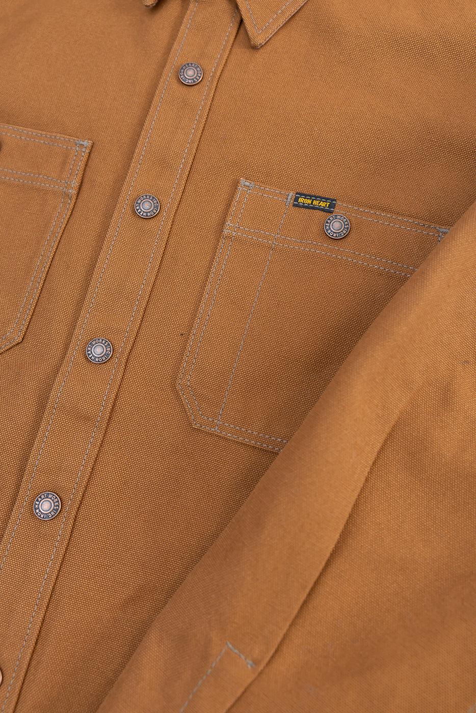 Close-up of front chest area of brown duck CPO work shirt, showing pocket, snap buttons, and fabric texture.