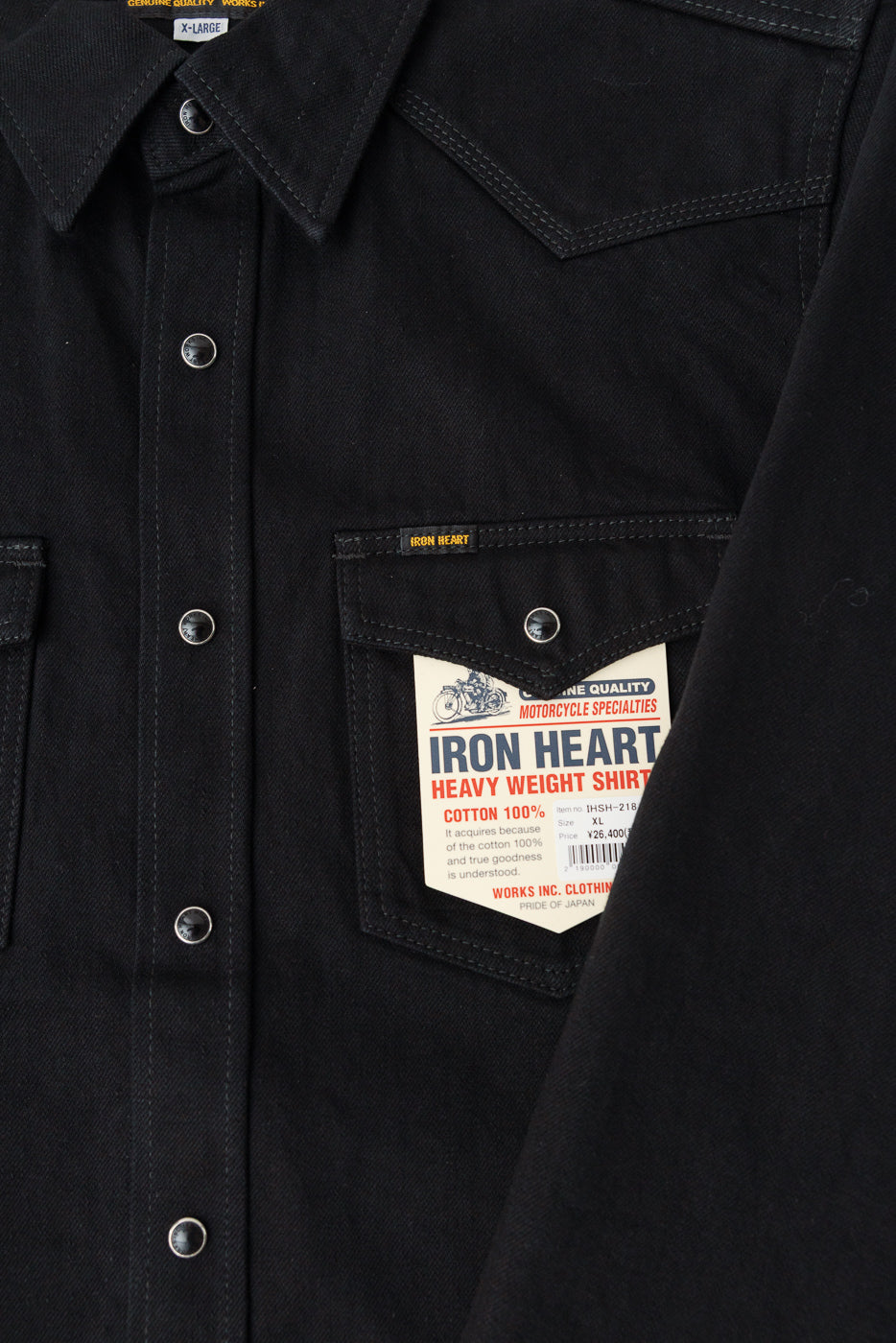 Close-up of Iron Heart IHSH-218 black selvedge denim western shirt front chest pocket showing snap buttons, pointed collar, and product tag detail.