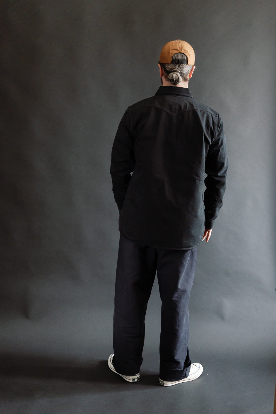 Male model 5'9 165lbs athletic build wearing Iron Heart IHSH-218-BLK 12oz selvedge denim western shirt, back view full body.