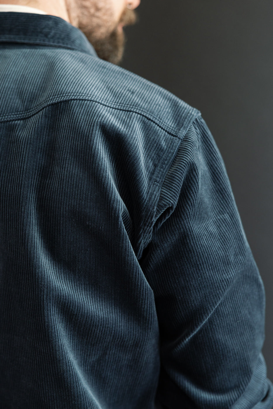 Close-up of back shoulder detail, navy corduroy western shirt on male model, showing fabric texture and yoke stitching.