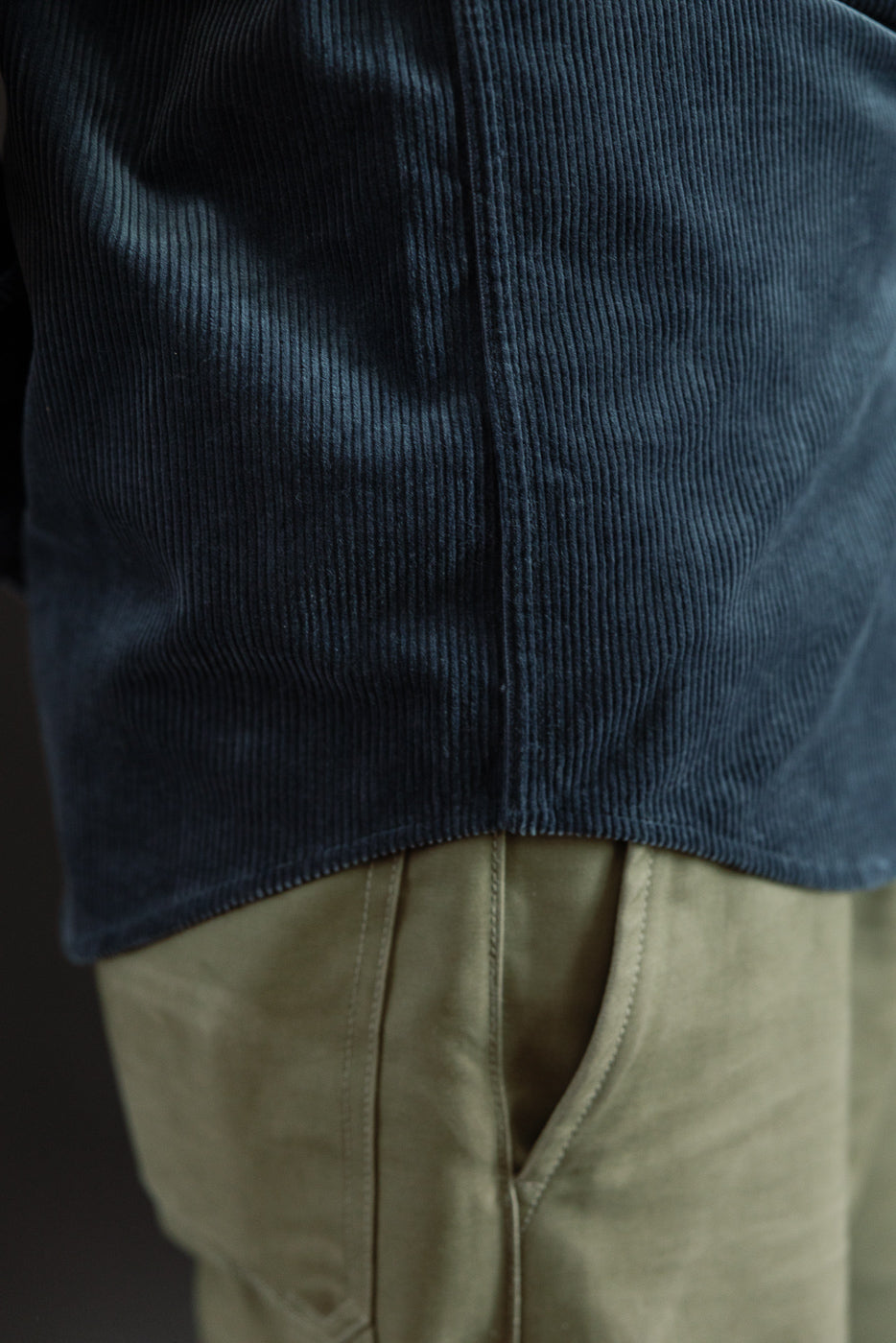 Close-up of male model's left side wearing navy corduroy shirt showing hem and texture
