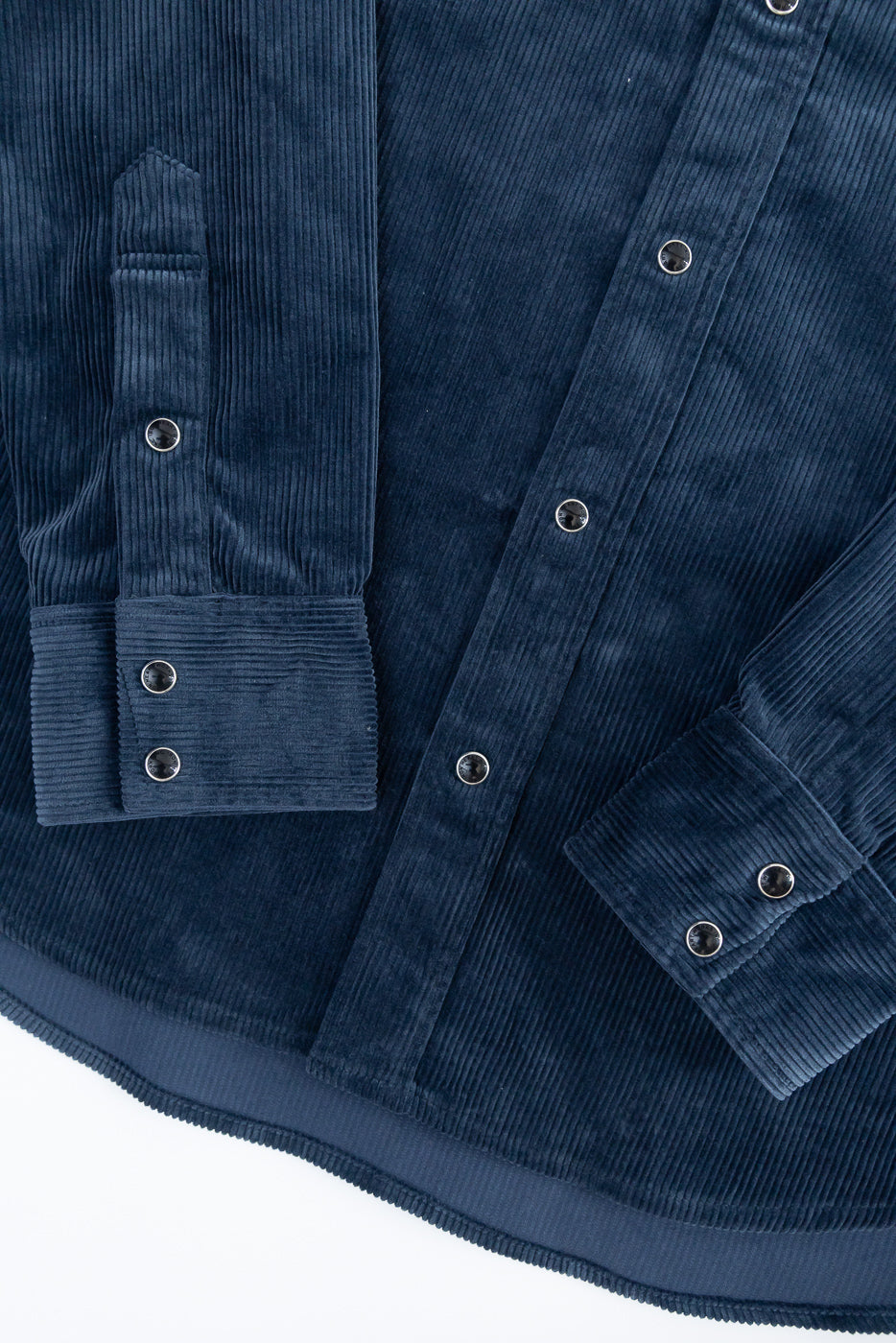 Close-up front view of navy corduroy shirt showing button details, sleeve cuffs, and ribbed texture