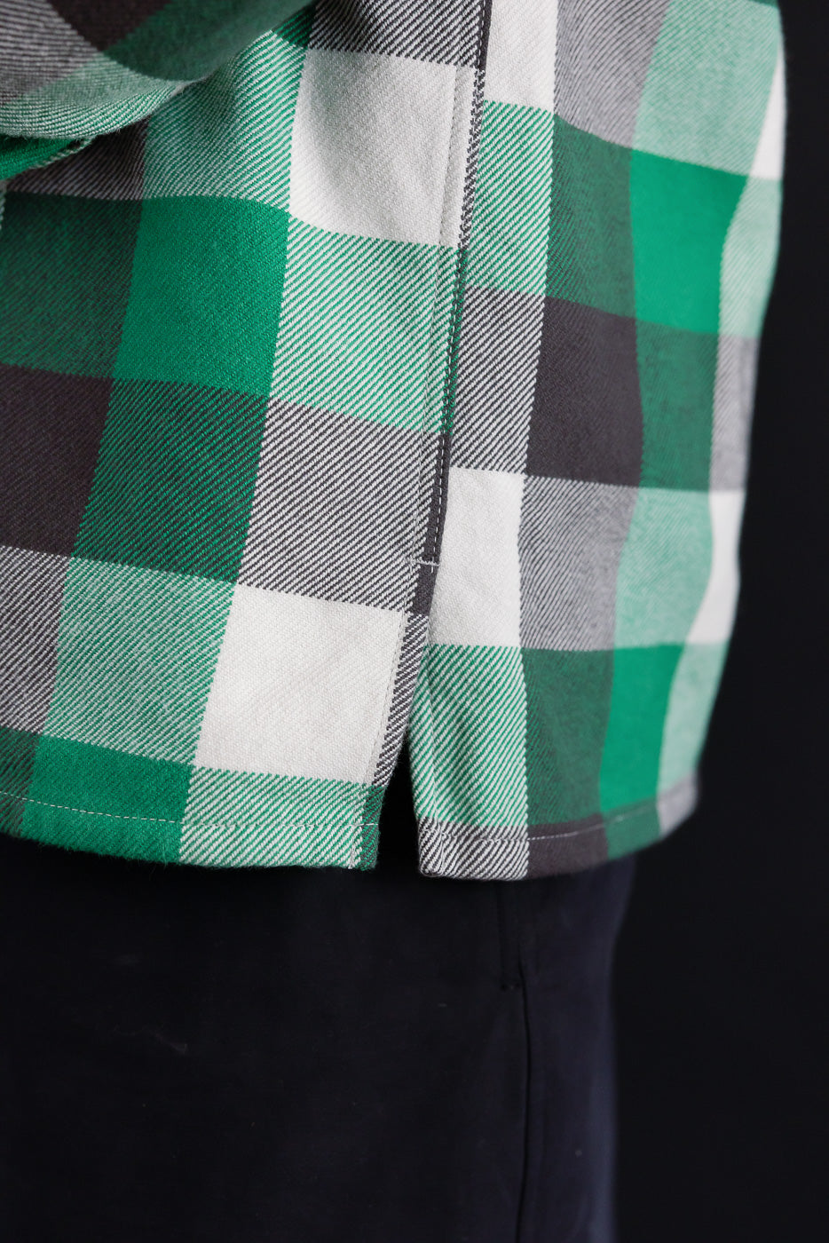 Close-up of Iron Heart green plaid flannel overshirt side hem, fabric detail visible.