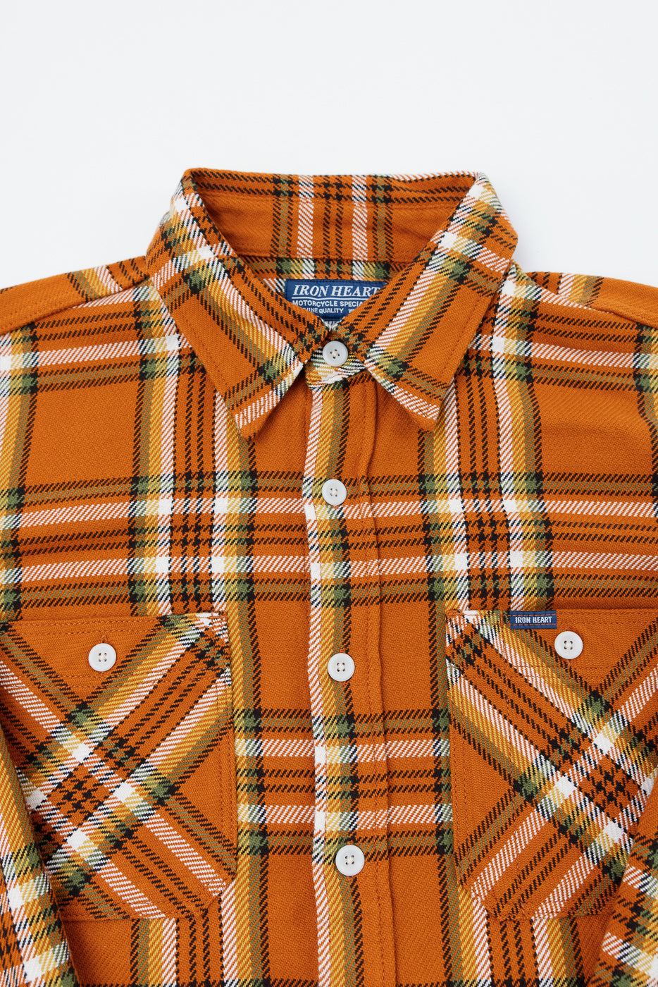 Close-up front view of orange plaid shirt with button-down collar, chest pockets, and Iron Heart tag