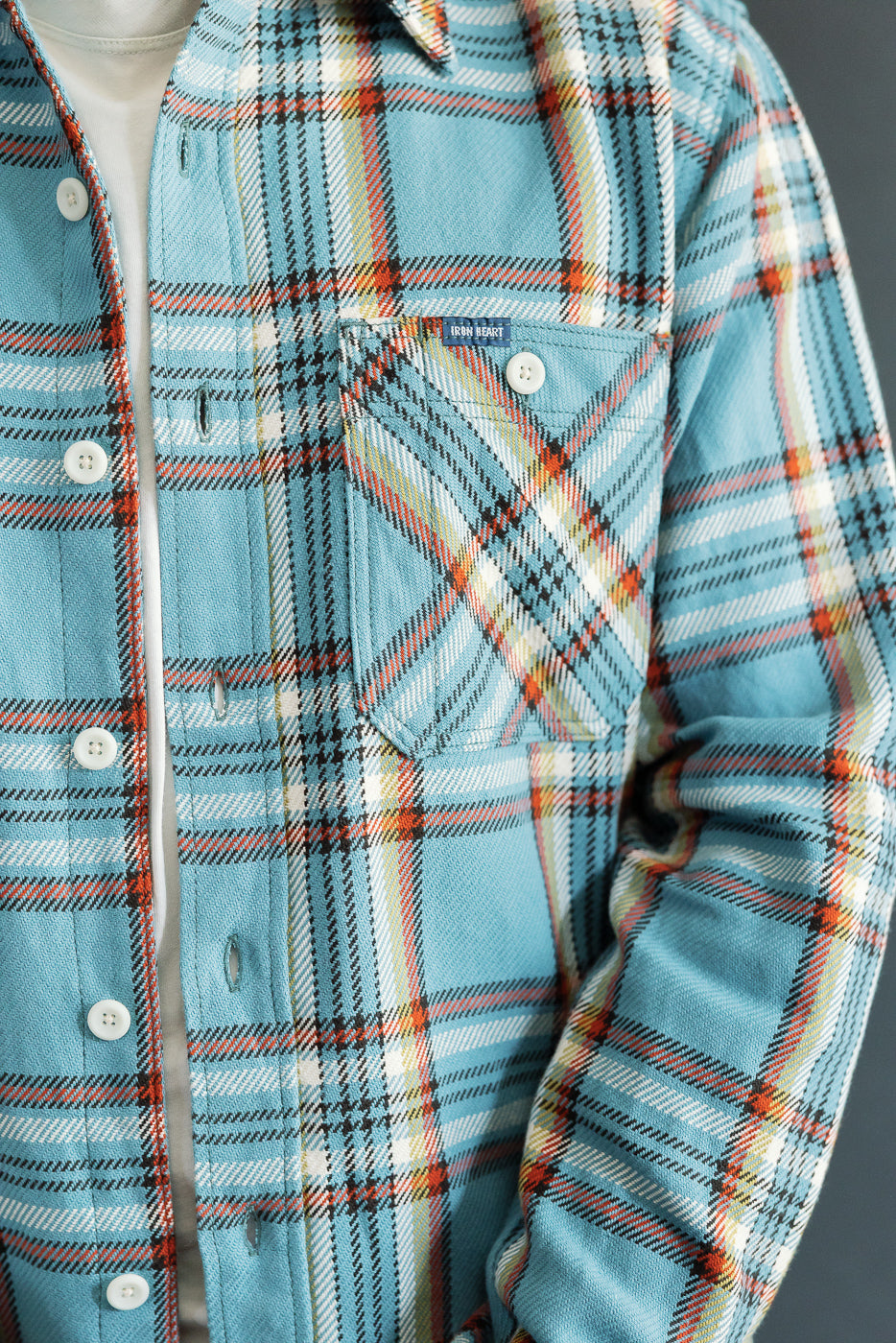 Close-up front view of male model's plaid shirt with chest pocket, buttons, and fabric texture details