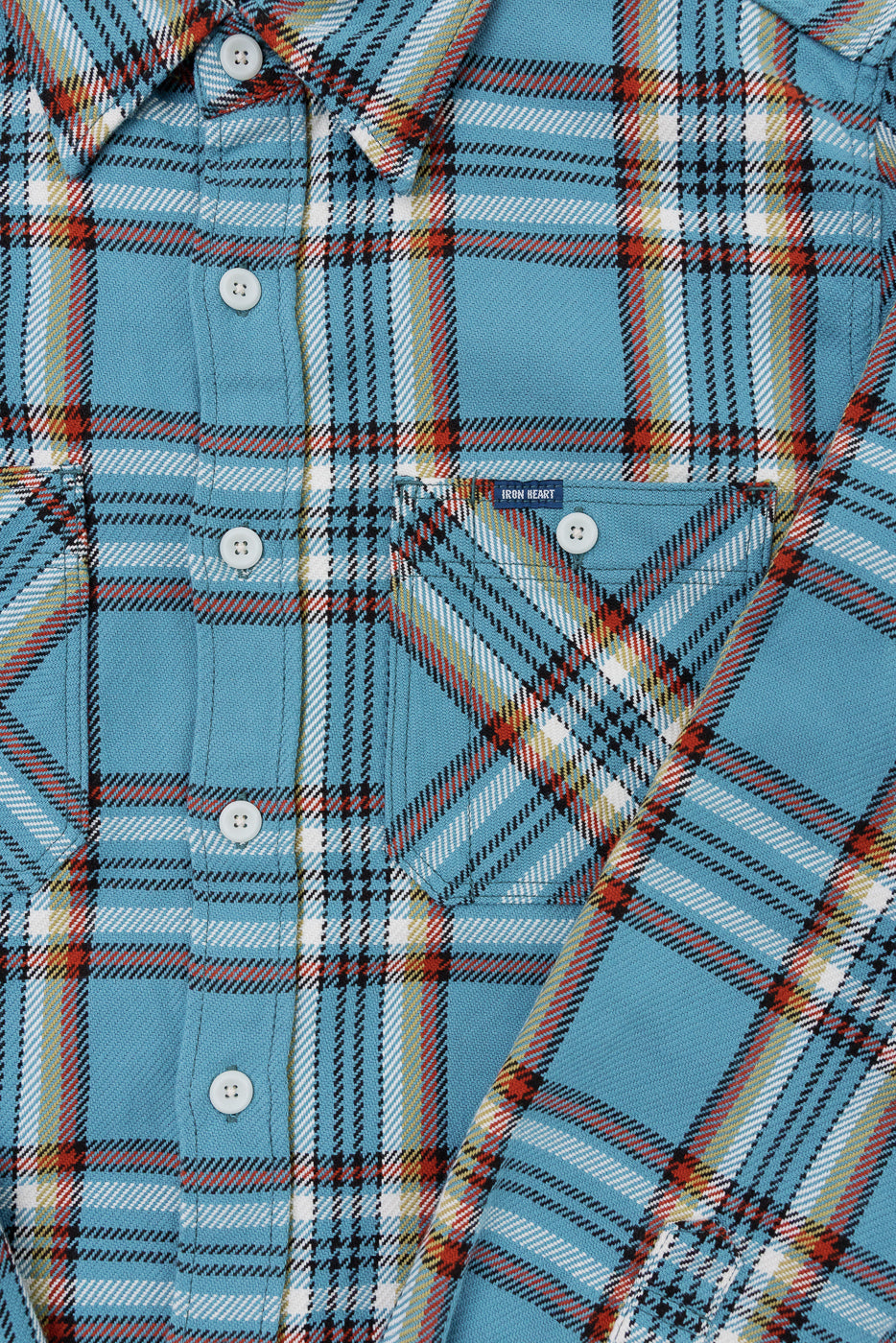 Close-up front view of blue plaid shirt with white buttons, chest pocket, and Iron Heart tag, showcasing fabric texture and pattern details