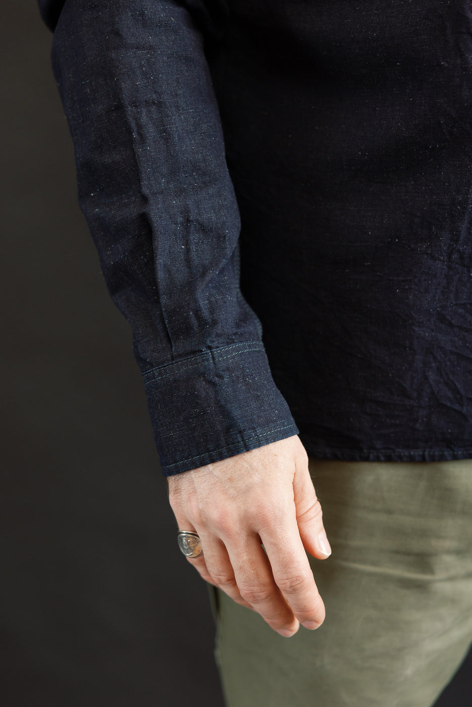 Close-up of male model's left arm showing indigo chambray work shirt sleeve cuff and fabric texture