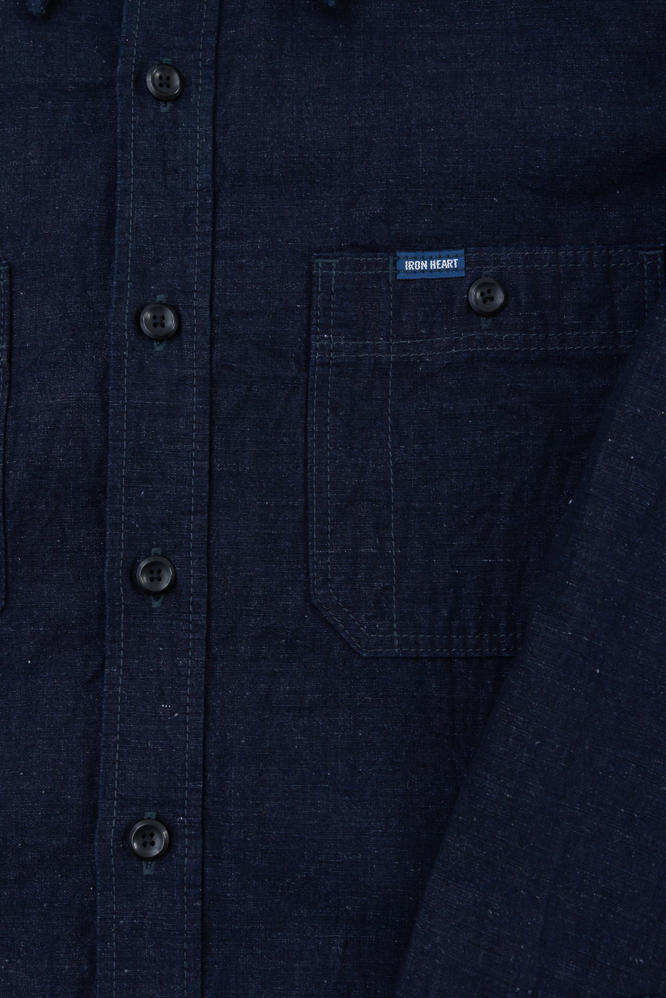 Close-up front view of indigo cotton linen chambray work shirt showing buttons, pocket, and fabric texture.