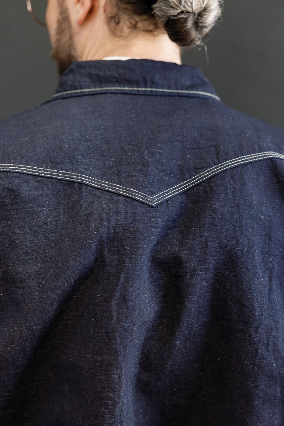 IHSH-444-IND - 7oz Cotton Linen Chambray Western Shirt features a V-shaped yoke seam with contrasting stitching on indigo fabric, highlighting its lightweight, breathable texture and meticulous Japanese craftsmanship.