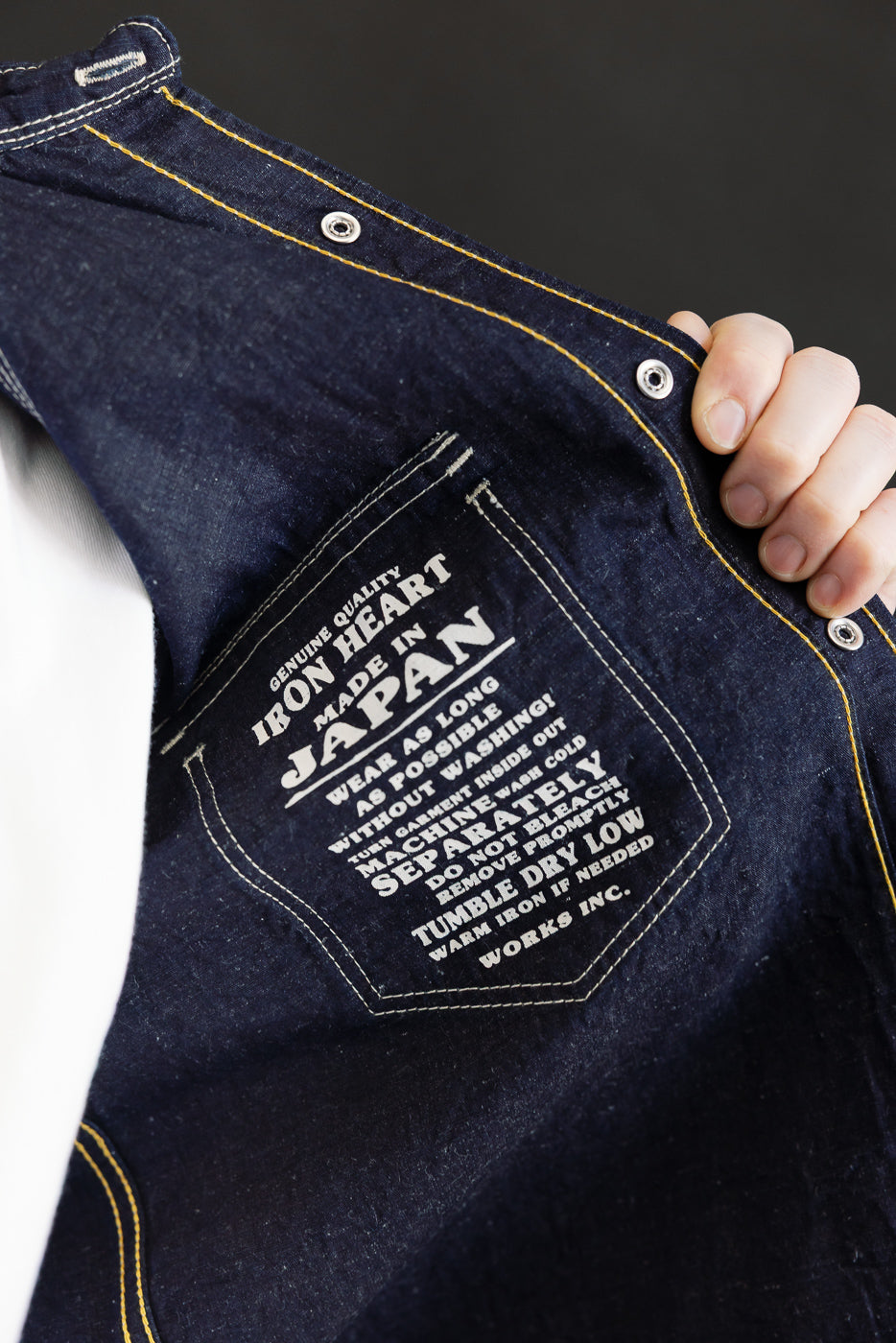 Close-up of IHSH-444-IND - 7oz Cotton Linen Chambray Western Shirt in indigo, showcasing the printed pocket-label of the denim jacket with Genuine Quality Iron Heart Made in Japan text.