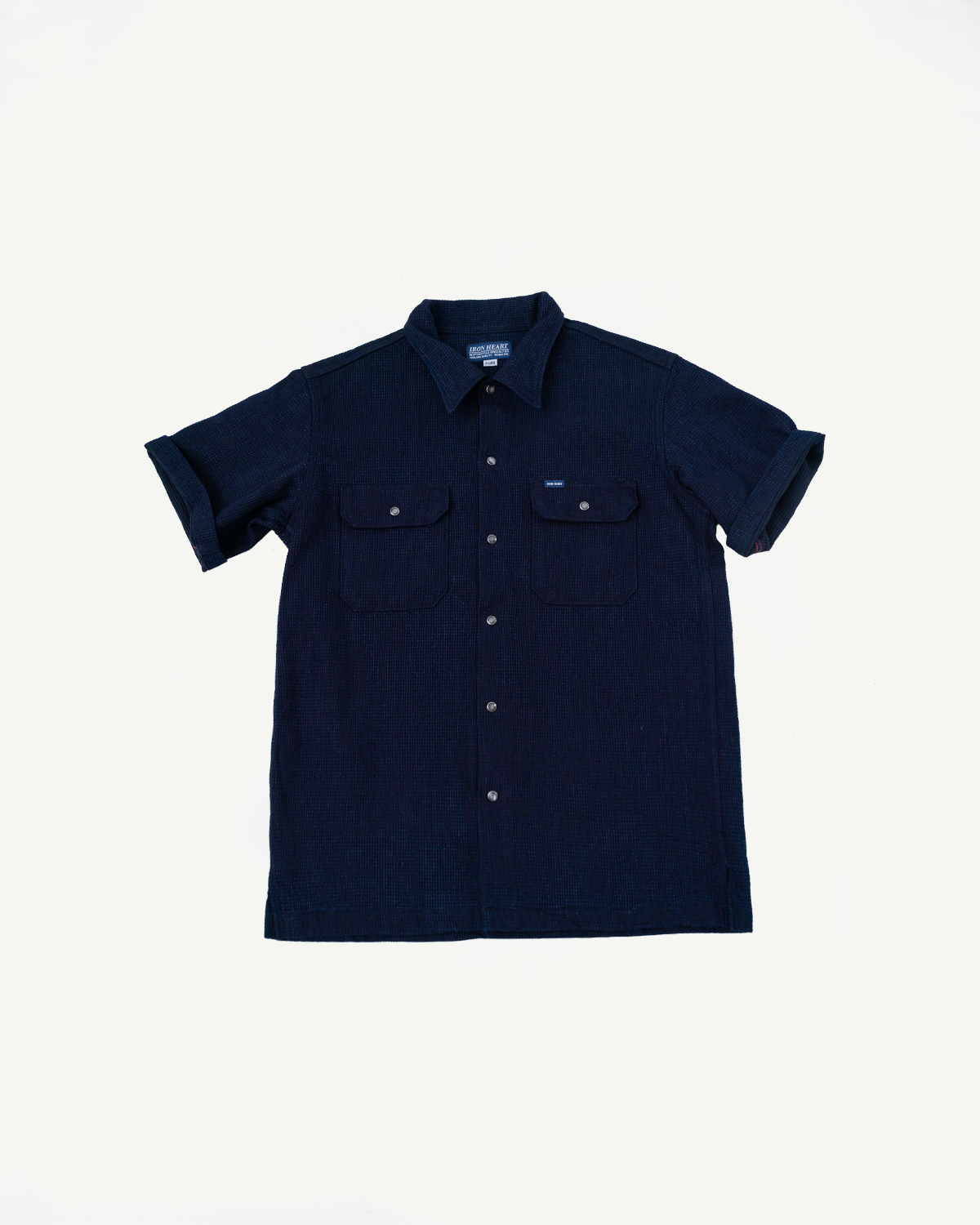 Front view of navy short-sleeve shirt with buttoned pockets, collar, and textured fabric