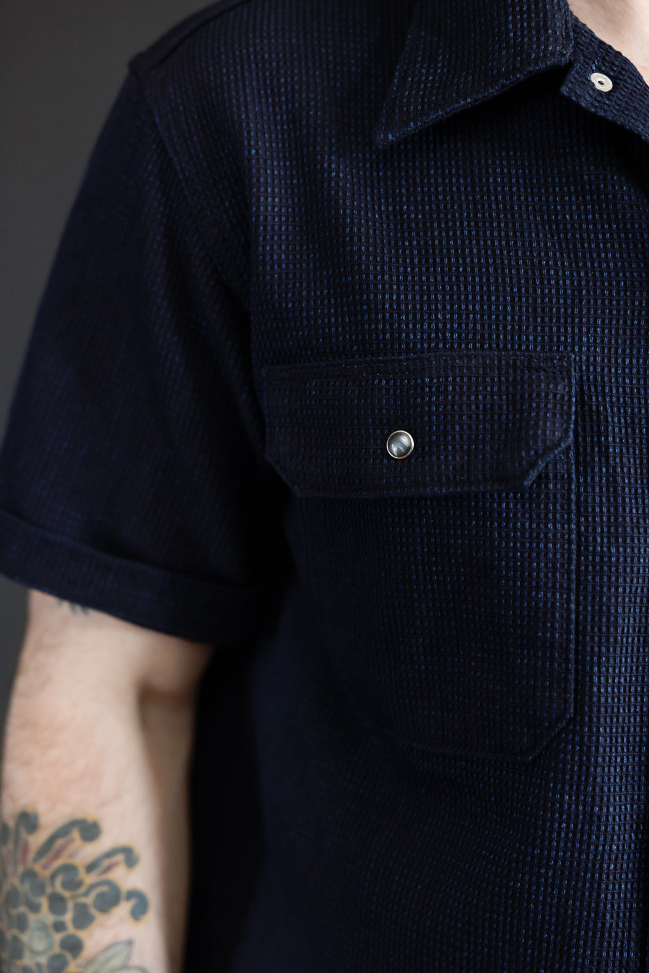 Close-up front view of navy textured short-sleeve shirt on male model, 5'9