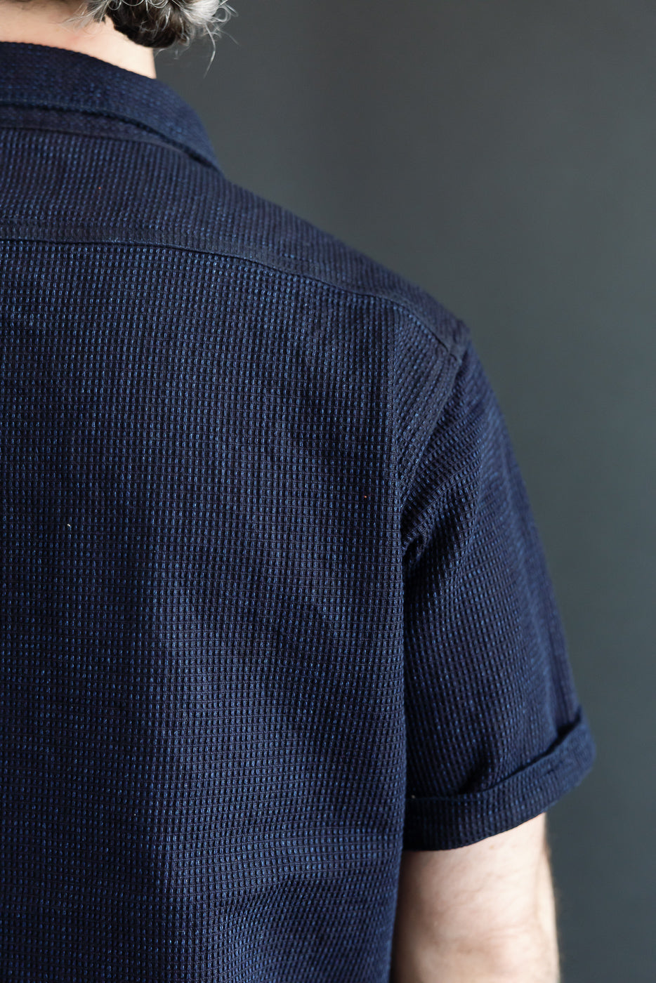 Back view of navy waffle knit short-sleeve shirt on male model, 5'9