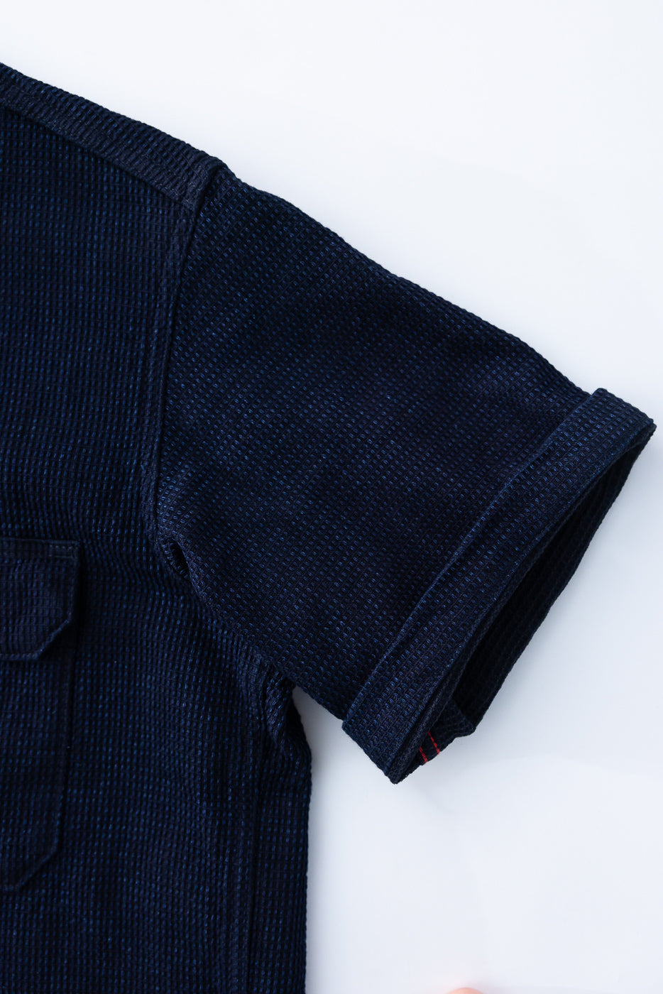 Close-up of navy waffle knit shirt sleeve, showing texture and red stitching detail