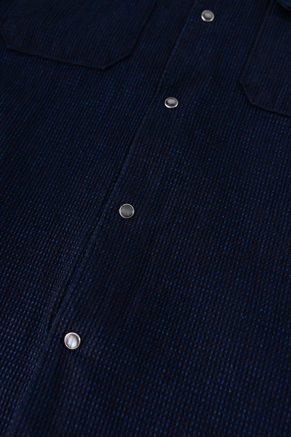 Close-up front view of navy shirt with textured fabric and metallic buttons