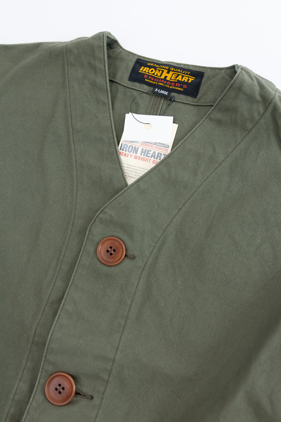 Close-up of olive duck canvas hunting vest front, showing buttons, V-neck collar, and brand tag.