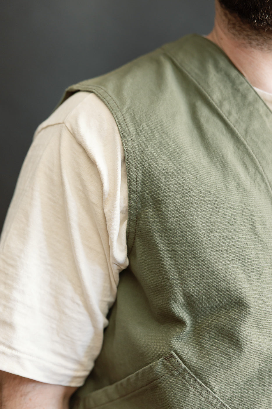 Close-up of olive duck canvas hunting vest, left front shoulder detail on male model, 5'9