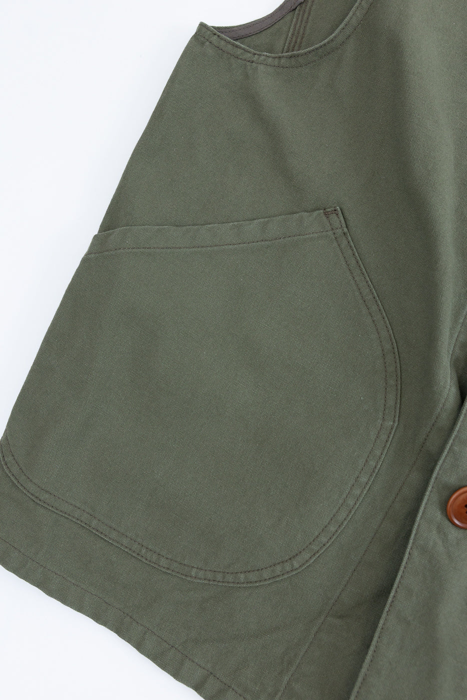 Close-up of olive hunting vest front left side pocket, showing canvas texture and stitching.