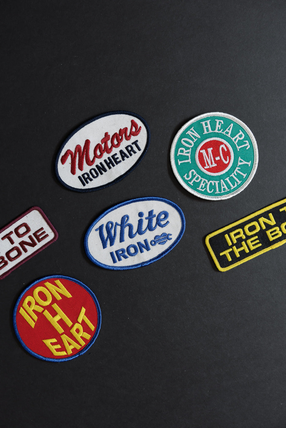 Iron Heart brand embroidered patches, front view, assorted shapes and colors on black background