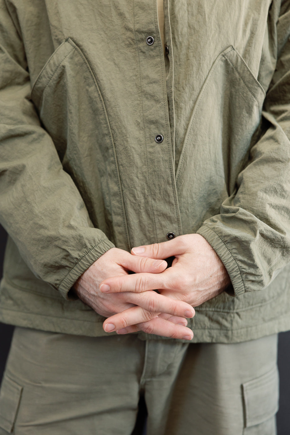 Close-up front view of olive green jacket buttons and fabric on male model, 5'9