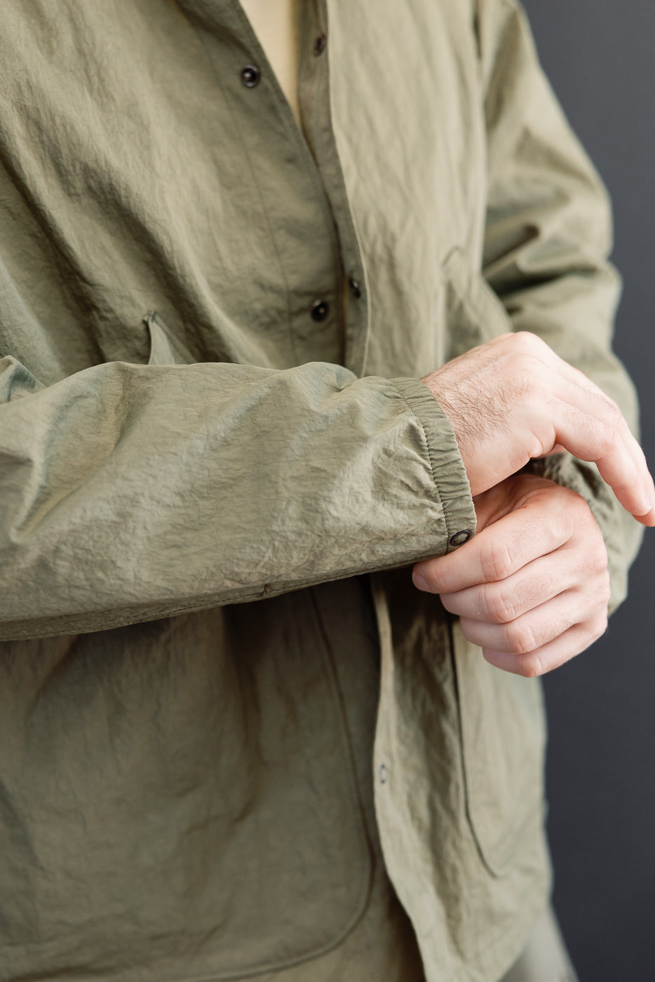 Close-up front view of olive green shirt cuff on a male model, 5'9