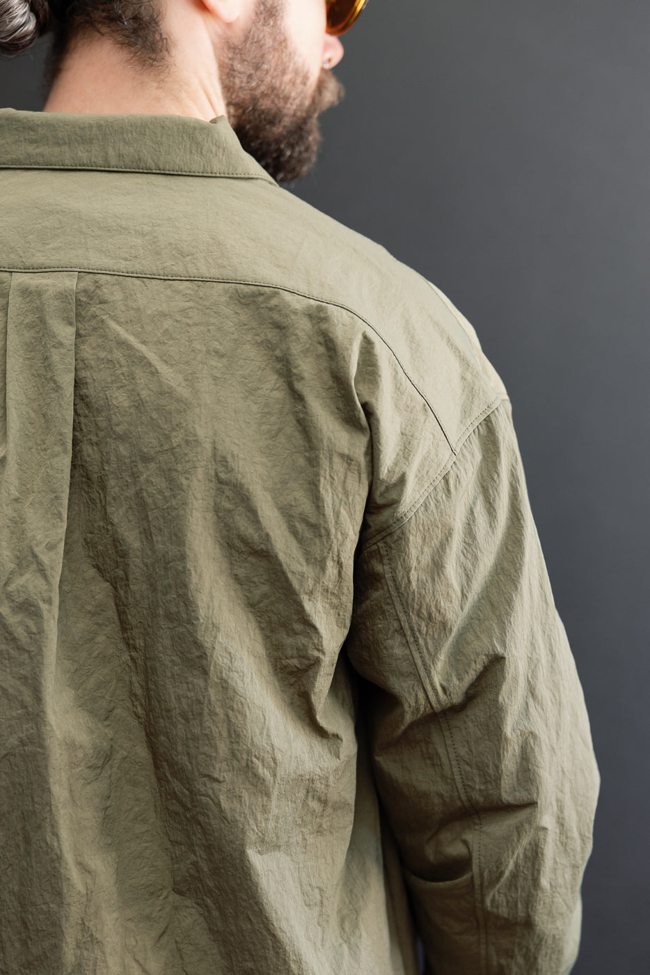 Close-up back view of olive green garment on male model, 5'9