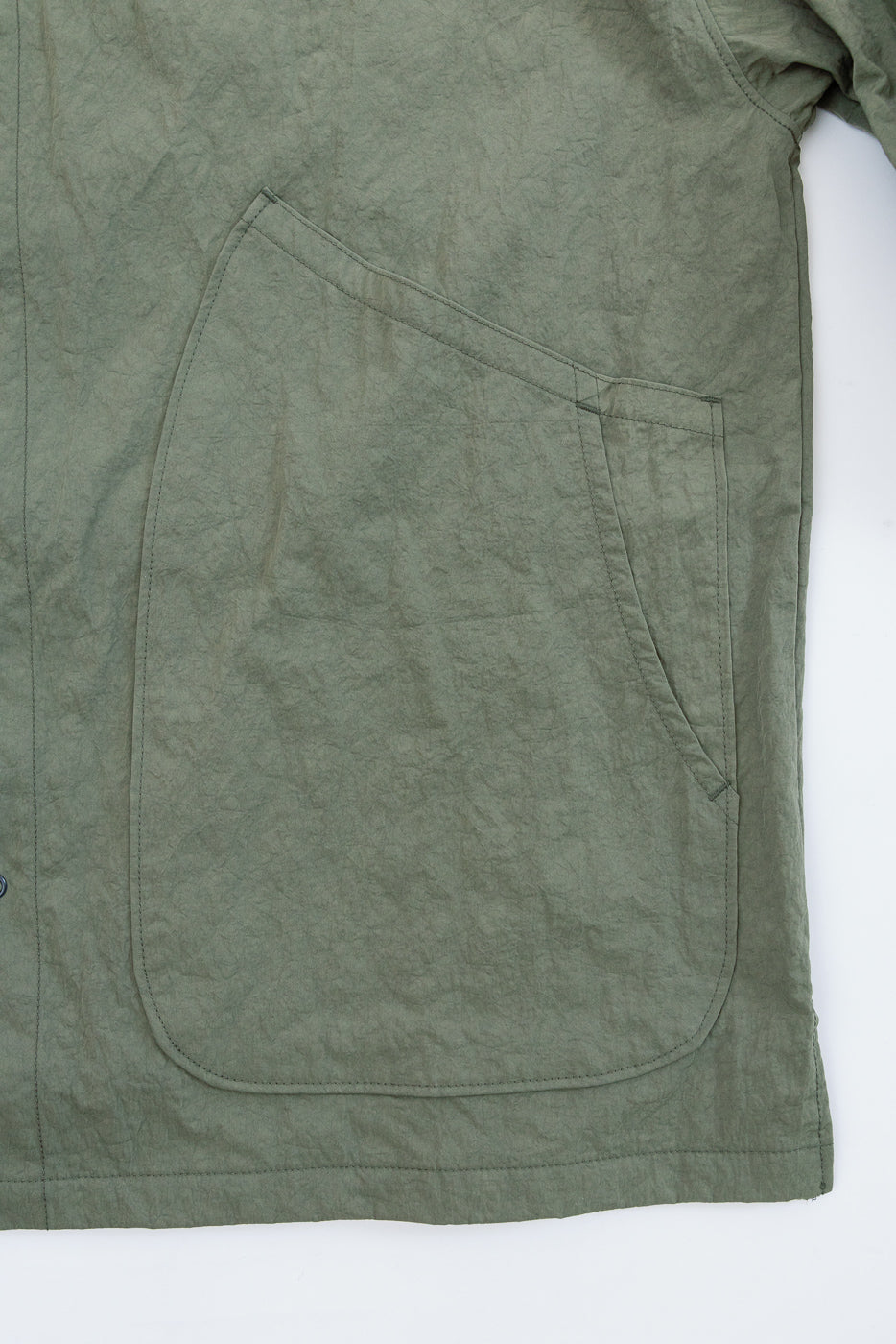 Close-up of the front left large patch pocket on a textured olive green garment.