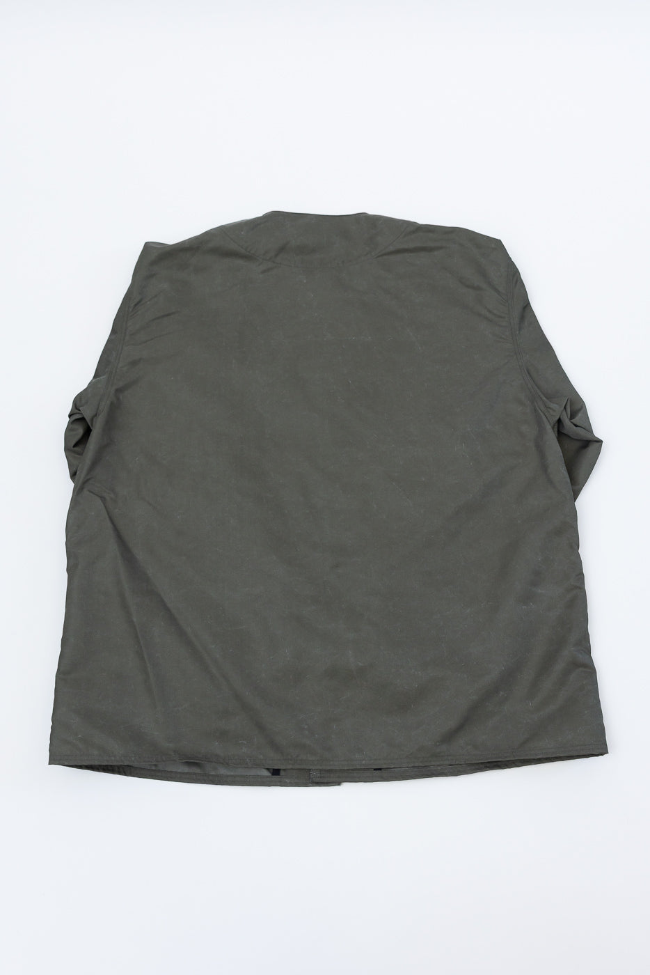 Flat lay of olive green collarless jacket, showing the back view and hem details.