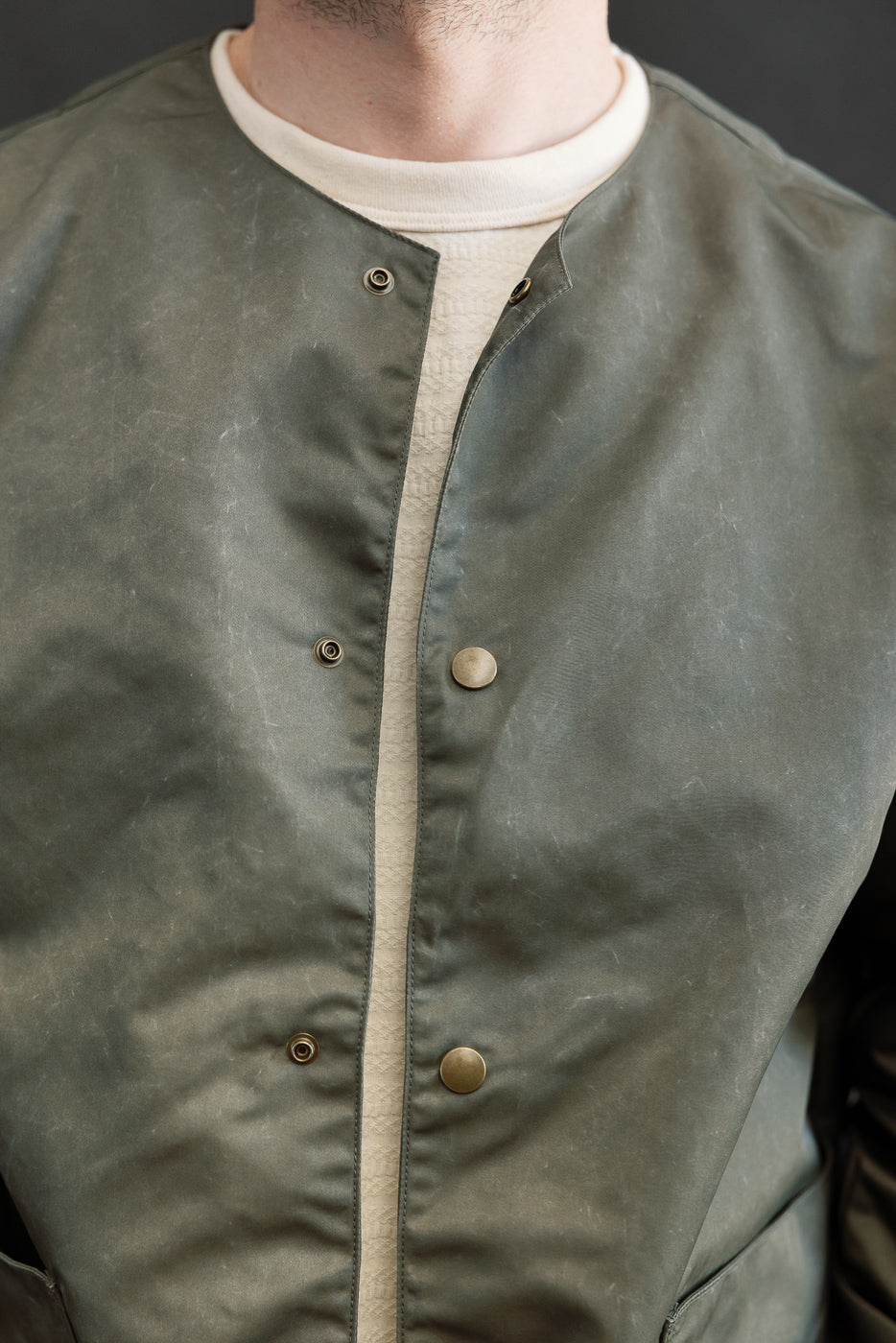 Close-up front view of olive collarless jacket on male model, 5'9
