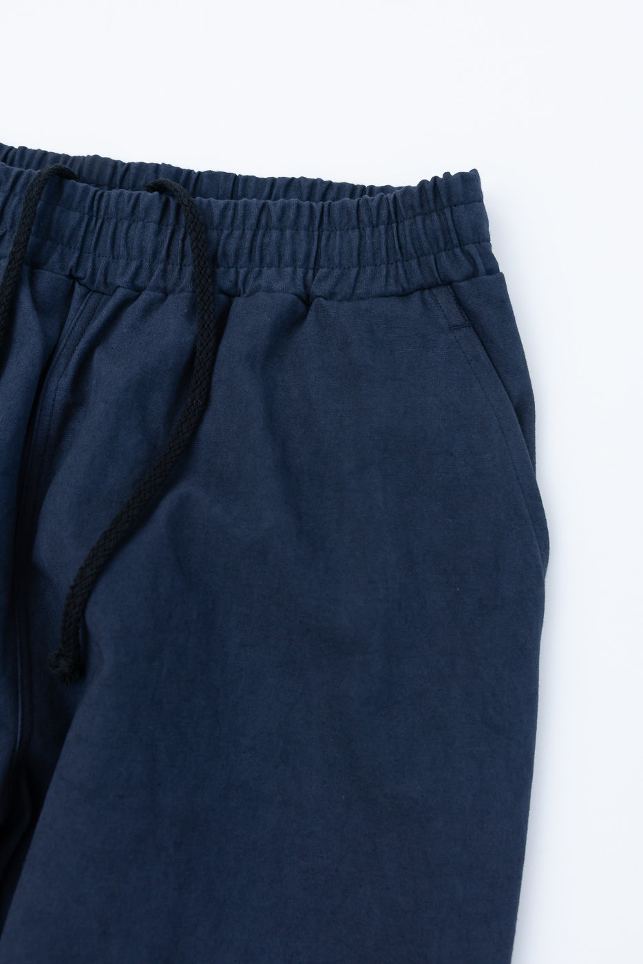 Close-up of front right side of navy canvas pants showing elastic waistband and drawstring details.