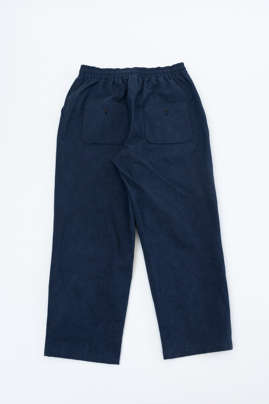 Flat lay back view of navy canvas pants with elastic waistband and two buttoned rear pockets.