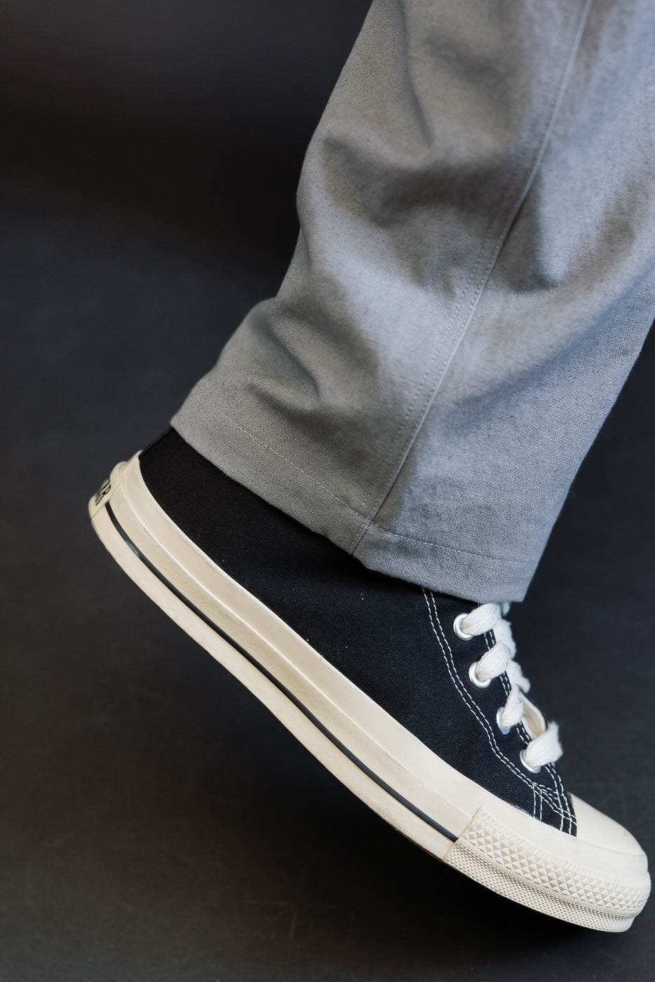 Close-up of male model's lower leg wearing gray canvas pants, side view of hem and shoe