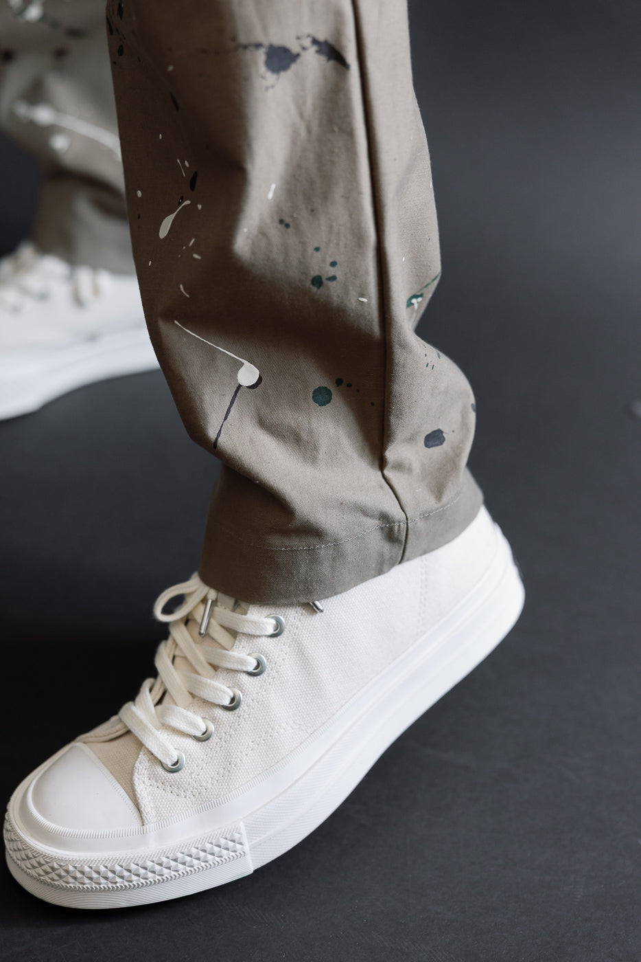 Close-up of the lower leg and white canvas sneakers on a male model, 5'9