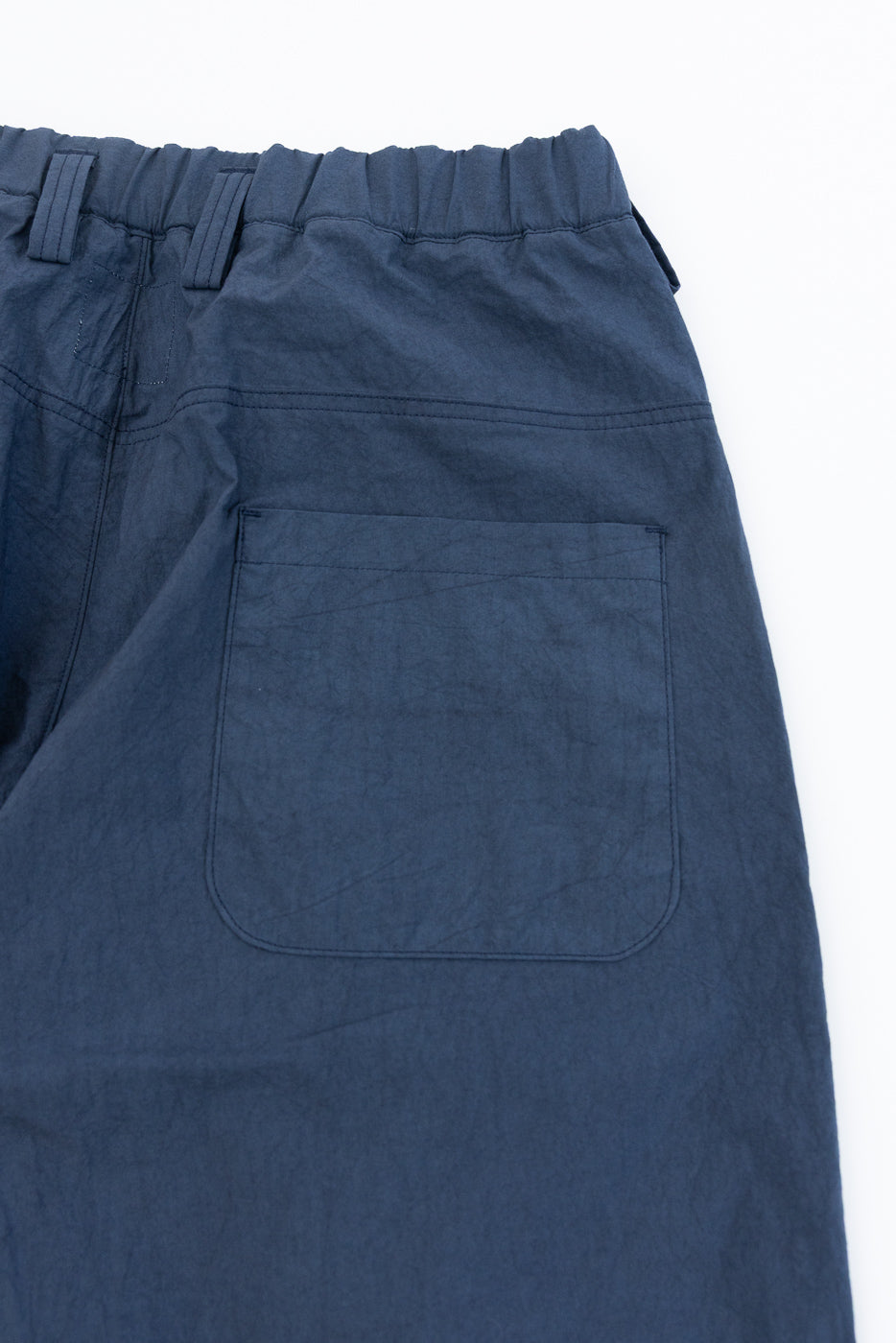 Close-up back view of navy casual pants showing elastic waistband, rear pocket, and fabric texture