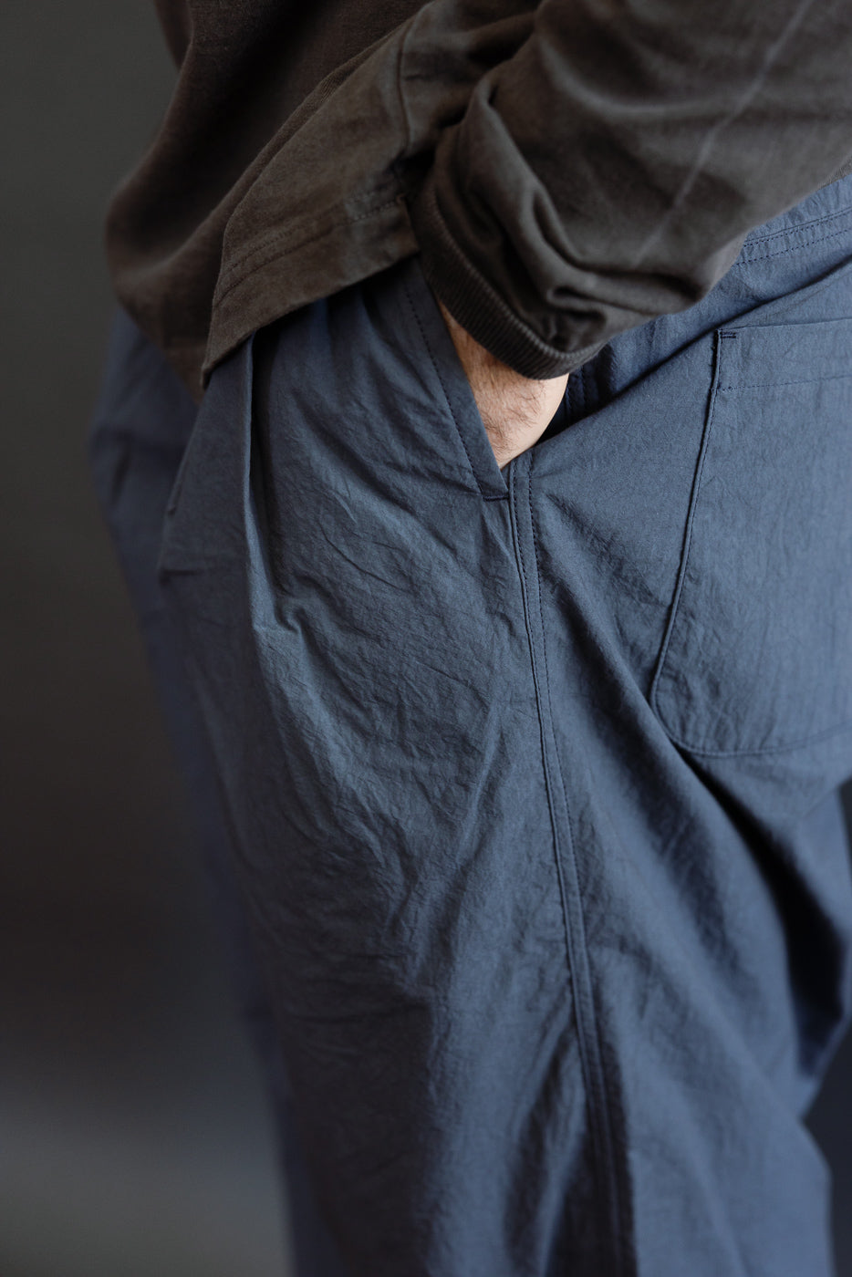 Close-up side view of male model’s navy casual pants showing front pocket, fabric texture, and relaxed fit