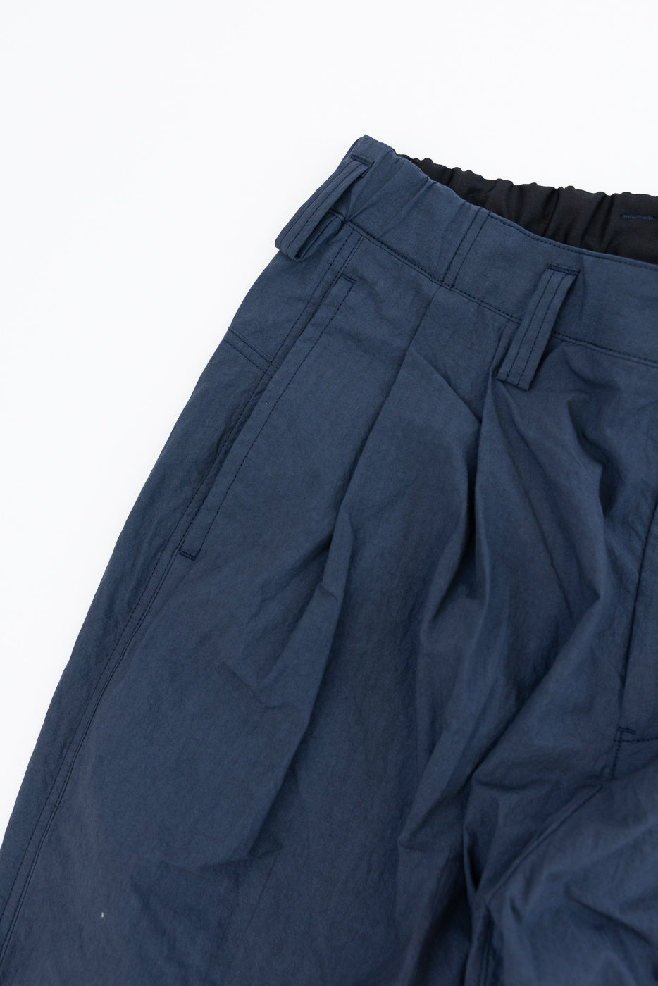 Close-up front view of navy casual pants with elastic waistband, pleats, and side pockets
