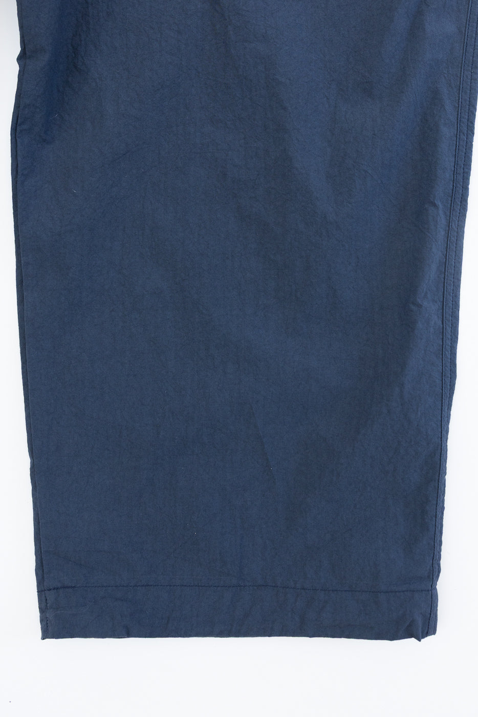 Flat lay close-up of navy casual pants front, showing hem and fabric texture