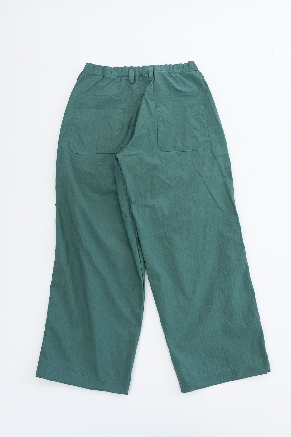 Back view of teal wide-leg pants with elastic waist and patch pockets, flat lay