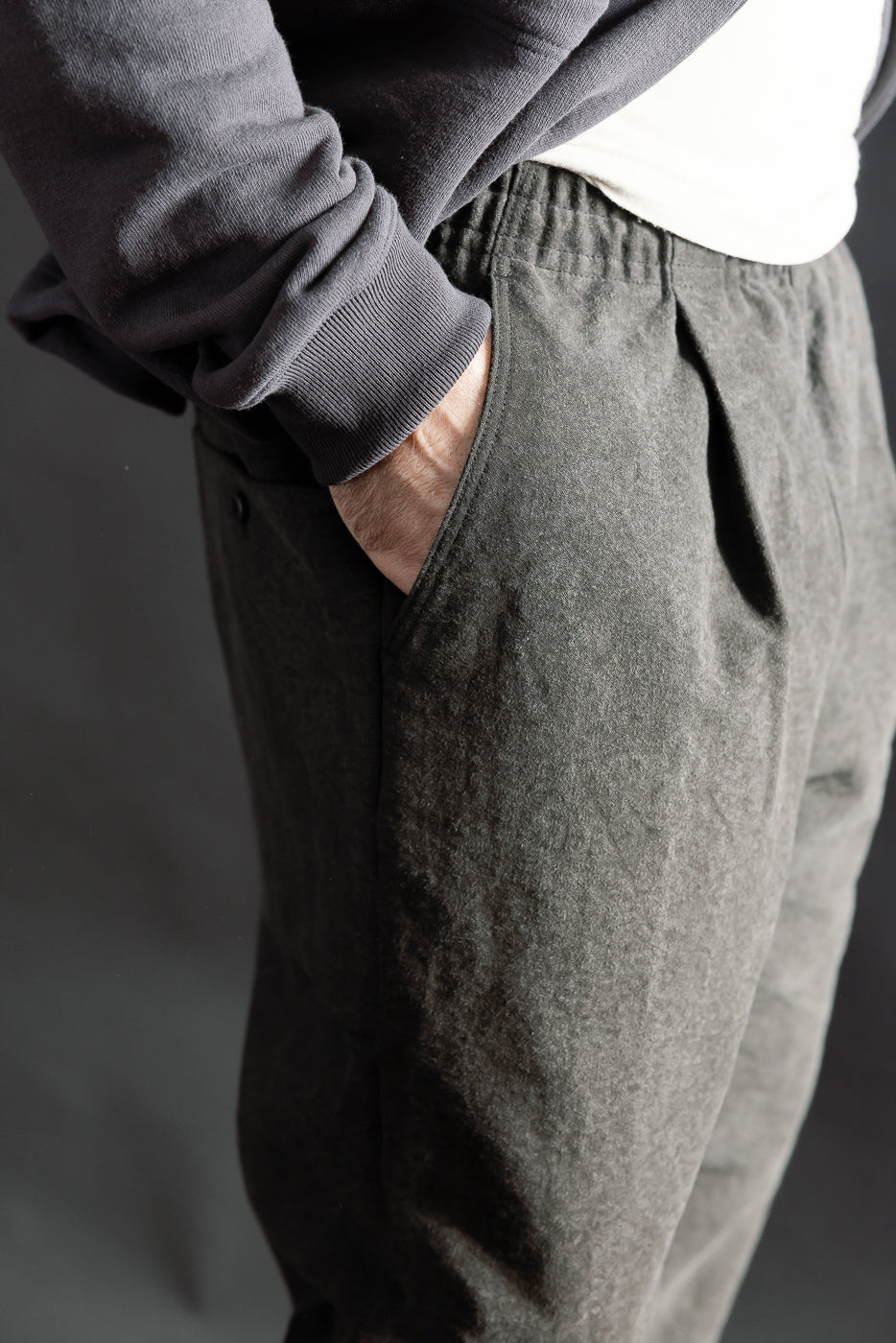 Close-up side view of black casual pants waistband and pocket, worn by male model 5'9