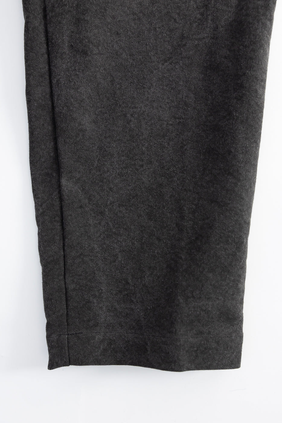 Close-up of black pant leg hem, front side, showing fabric texture, Dant contemporary apparel.