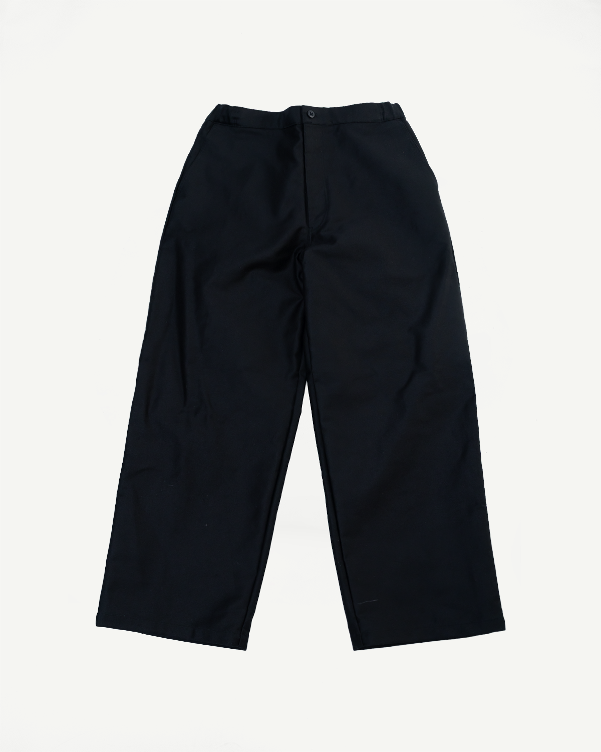 Flat lay, front view of black baggy moleskin trousers showing waistband and button.