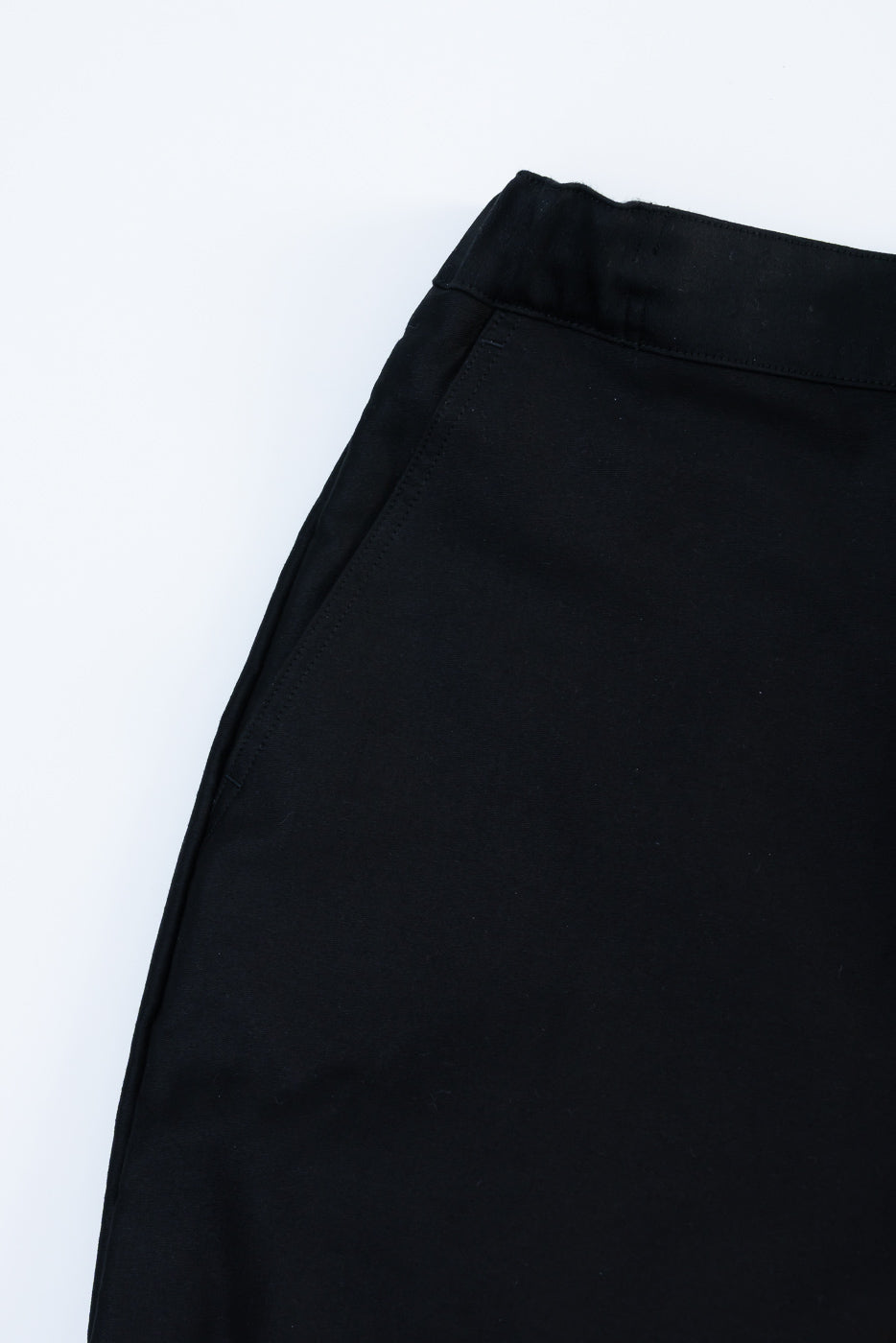 Close-up of black moleskin trouser, flat lay, front left waist and pocket detail visible