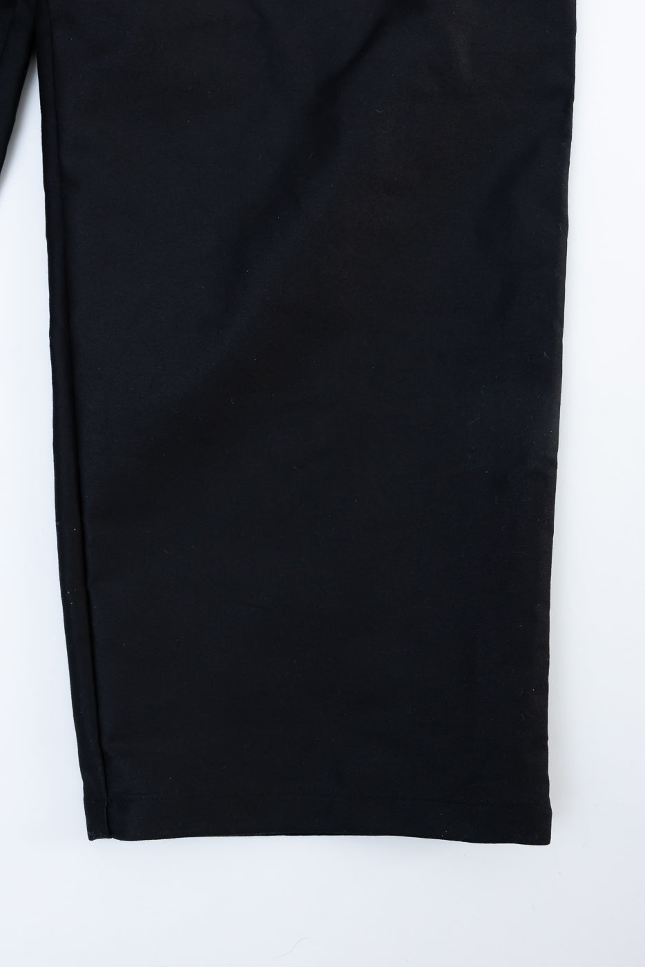 Close-up of black moleskin trouser leg, front side, showing fabric texture and hem stitching.